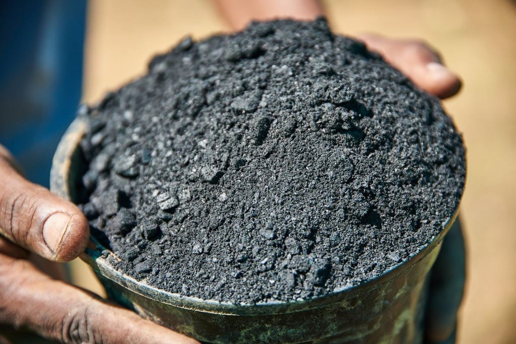 farmer's hands holding soil in a crop field