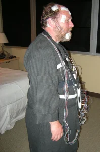 A sleep-study participant rests in bed while monitoring sensors record the night.