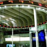 Multiple stock market trading screens displaying charts, prices and financial data in a trading room.
